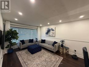 Mississauga (Erin Mills) apartment for rent - A living room with a grey sofa, a blue ottoman, and a painting on the wall.
