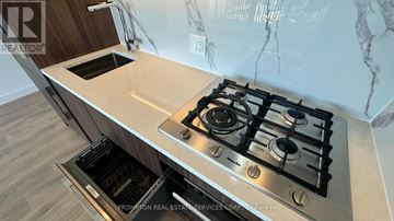 Toronto (Bayview Village) condo for rent - A modern kitchen with a stainless steel gas stove and a marble backsplash.