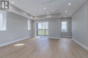 Oshawa (Vanier) triplex for rent - A spacious room with wooden flooring and a balcony with a railing.