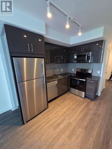 Toronto (Humber Heights) condo for rent - A modern kitchen with a stainless steel refrigerator and wooden flooring.