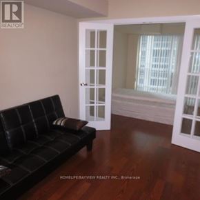 Toronto (Bay Street Corridor) condo for rent - A black couch sits in a room with a doorway leading to a balcony.
