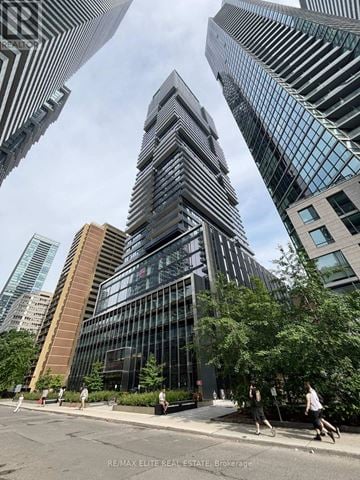 Toronto (Church-Yonge Corridor) townhouse for rent - A tall building with a glass facade stands in the middle of a city street.