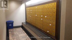 Richmond Hill (Langstaff) condo for rent - A wall of mailboxes in a hallway with a trash can and a brokerage sign.