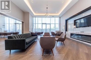 Vaughan condo for rent - A modern living room with a long black sofa and a fireplace.