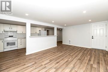 Ottawa apartment for rent - A spacious kitchen with white cabinets and a wooden floor.