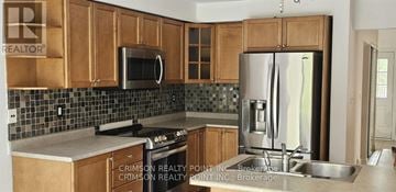 Oshawa (Pinecrest) apartment for rent - A kitchen with wooden cabinets and a stainless steel refrigerator.