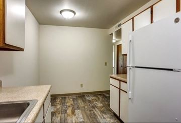 Paw Paw apartment for rent - A kitchen with a white fridge, sink and wooden cabinets.