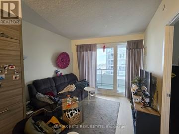 Toronto (Mount Pleasant West) condo for rent - A living room with a black couch and a TV on the right side.