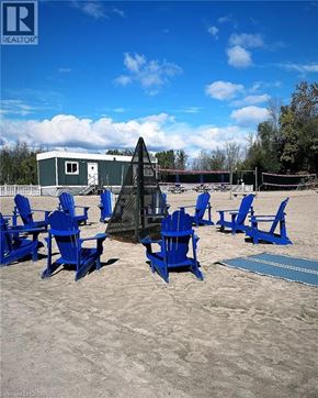 Innisfil condo for rent - A beach scene with blue chairs and a volleyball net.