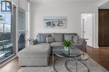 Innisfil condo for rent - A living room with a grey couch and a glass coffee table.