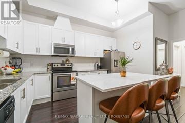 Niagara Falls (Mt. Carmel) condo for rent - A kitchen with white cabinets and a large island with brown chairs.