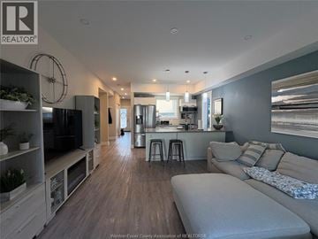 Windsor townhouse for rent - A modern living room with a grey sofa and a kitchen area in the background.