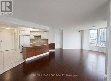 Toronto (Willowdale East) condo for rent - A spacious room with wooden flooring and white walls.