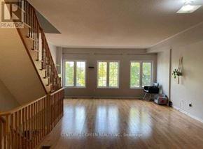 Toronto (Scarborough Village) apartment for rent - A spacious room with a staircase on the left and a large window with a view of trees.