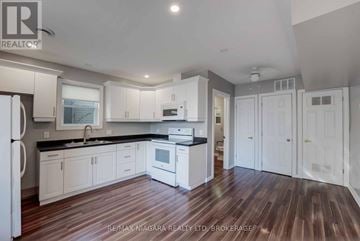 Niagara Falls (Church's Lane) apartment for rent - A kitchen with white cabinets and a wooden floor.