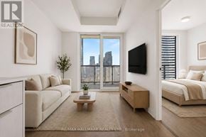 Toronto (Church-Yonge Corridor) condo for rent - A living room with a large window overlooking a city skyline.