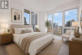 Toronto (Church-Yonge Corridor) condo for rent - A bedroom with a large bed, a nightstand, a chair, and a view of the city.