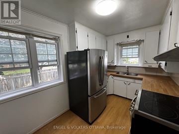 Ottawa apartment for rent - A kitchen with white cabinets and a black fridge.