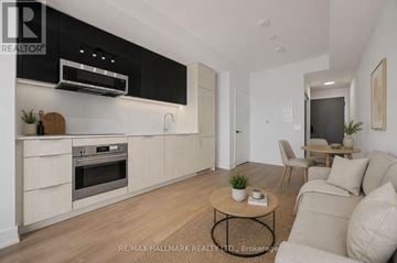 Toronto (Church-Yonge Corridor) condo for rent - A modern kitchen with a black range hood above the stove and a wooden coffee table in the center of the room.