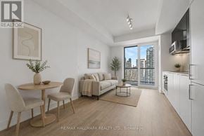 Toronto (Church-Yonge Corridor) condo for rent - A well-lit, modern living room with a dining table and chairs, a sofa, and a kitchen area with white cabinets.