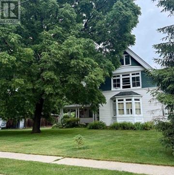 Brampton (Downtown Brampton) multi-family for rent - A white house with a green roof is surrounded by trees.