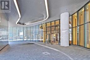 Toronto (Bay Street Corridor) condo for rent - The image shows the entrance to a building with a glass facade and a stone pillar in front.
