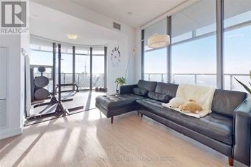 Toronto (Bay Street Corridor) condo for rent - A living room with a black couch and a wooden floor.