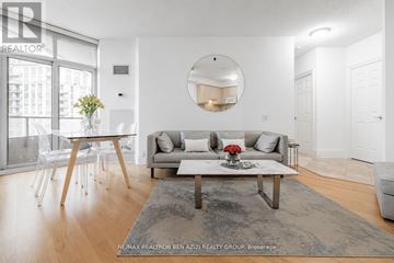 Toronto (Willowdale East) condo for rent - A modern living room with a grey rug, a white sofa, a wooden coffee table and a round mirror on the wall.