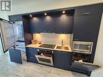 Toronto (Dovercourt-Wallace Emerson-Junction) condo for rent - A modern kitchen with dark blue cabinets and stainless steel appliances.