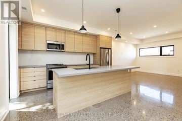 Toronto (Dovercourt-Wallace Emerson-Junction) apartment for rent - A modern kitchen with wooden cabinets and a granite countertop.
