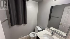 Kitchener apartment for rent - A bathroom with a toilet, sink, and mirror.