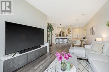 Milton (Om Old Milton) condo for rent - A modern living room with a large television and a coffee table with flowers on it.