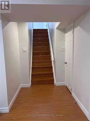 Toronto (Milliken) apartment for rent - A wooden staircase leads up to a white door.