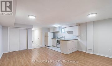 Brampton (Brampton South) apartment for rent - A spacious kitchen with white cabinets and a wooden floor.