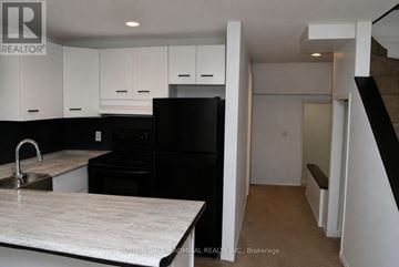 Toronto (South Riverdale) multi-family for rent - A kitchen with black appliances and white cabinets.