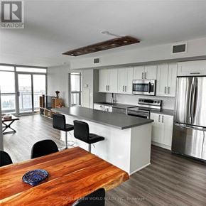 Toronto (Waterfront Communities) condo for rent - A modern kitchen with a wooden table and stainless steel appliances.