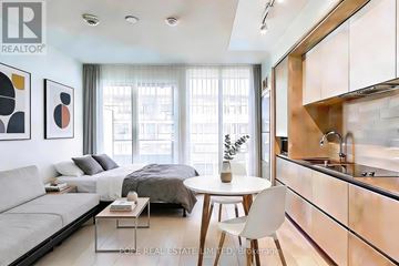 Toronto (Regent Park) condo for rent - A modern bedroom with a large bed and a kitchen area with a sink.