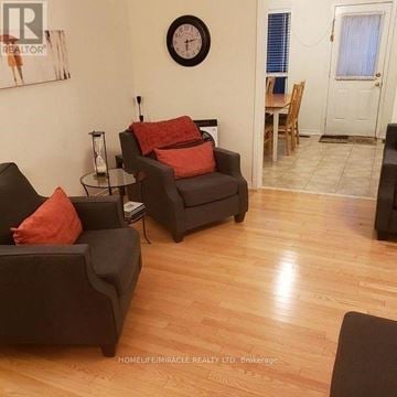 Brampton (Bram East) townhouse for rent - A living room with a black couch and a clock on the wall.