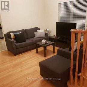 Brampton (Bram East) townhouse for rent - A living room with a grey couch, a black coffee table, and a television.