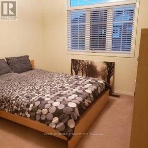 Brampton (Bram East) townhouse for rent - A bedroom with a bed covered in a black and white patterned bedspread.