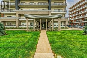 Hamilton condo for rent - A large building with a green lawn in front and a walkway leading to the entrance.