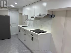 St. Catharines (Carlton/Bunting) apartment for rent - A white kitchen with a black stove top and a refrigerator.