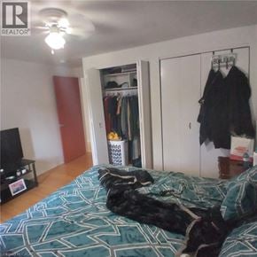 Kitchener apartment for rent - A bedroom with a bed, a TV, a wardrobe and a dog.
