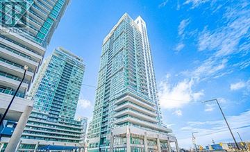 Toronto (Bendale) condo for rent - A tall building with a glass facade stands in front of other buildings.
