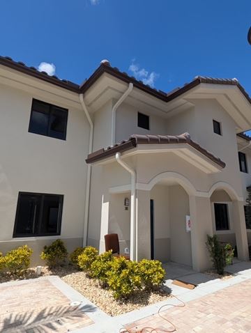 Hialeah apartment for rent - A house with a brown roof and white walls with a small garden in front.