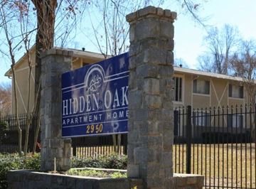 Atlanta apartment for rent - A sign for Hidden Oak Apartment Home stands in front of a building.