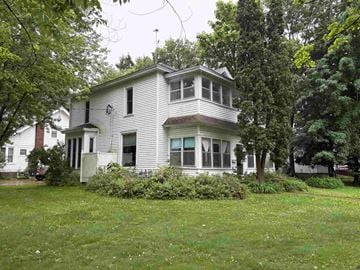 Menomonie apartment for rent - A white house with a green lawn in front.