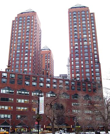 New York apartment for rent - Two red brick buildings with many windows in front of a white sky.