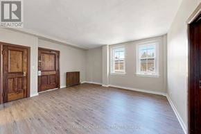 Halton Hills (Georgetown) apartment for rent - A room with wooden floors and white walls, with a window showing a view of a tree and a building.
