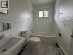 Brantford apartment for rent - A white bathroom with a tub, toilet and sink.